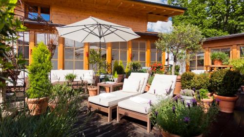 a patio with white chairs and an umbrella at Superior Hotel Tirolerhof - Zell am See in Zell am See