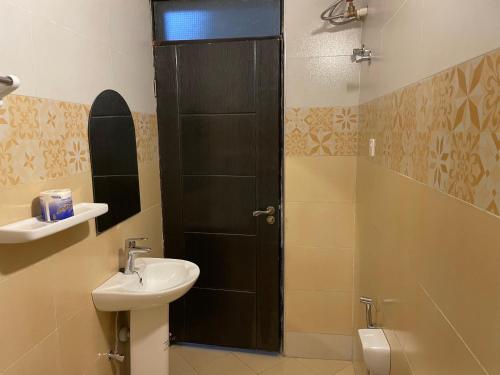 a bathroom with a sink and a shower with a black door at Jaffa Suites in Kampala