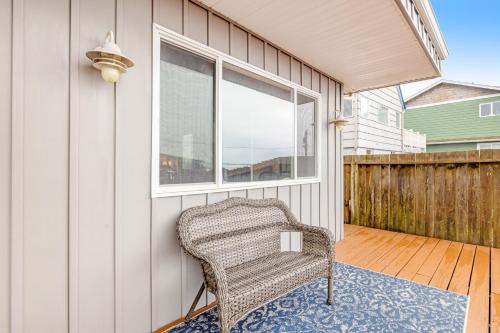 a wicker chair sitting on a porch with a window at Cozze Cottage in Wecoma Beach