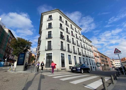 Un edificio bianco in una strada con gente che cammina davanti di Tulem La Latina a Madrid