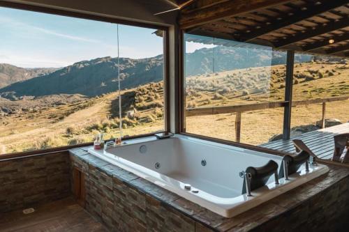 a bath tub in a room with a view of the mountains at CASAS VIEJAS LODGE in La Cumbrecita