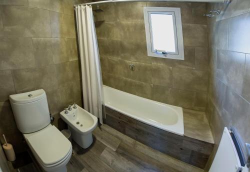 a bathroom with a toilet and a tub and a sink at Altos de Manantiales in El Calafate