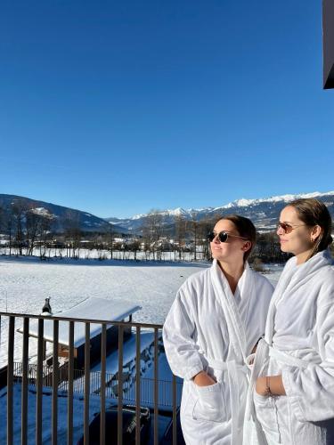 two women dressed in white standing next to a body of water at B&B Boutique Apartment Oberwiesen in Brunico
