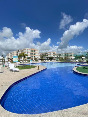 ein großer Swimmingpool in einem Resort mit Gebäuden im Hintergrund in der Unterkunft Muro Alto Condomínio Clube Apto 219 in Ipojuca