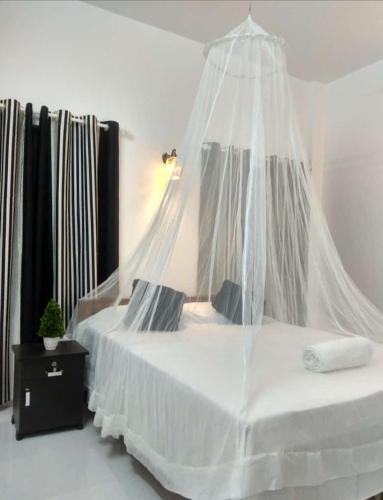 a bedroom with a white bed with a mosquito net at CLIFF HEAVEN in Varkala