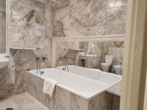 a white bath tub in a marble bathroom with a sink at Leoton Chernivtsi in Chernivtsi