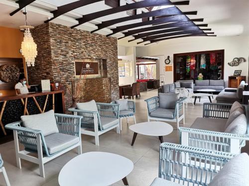 un hall avec des chaises et des tables ainsi qu'un mur en briques dans l'établissement Laguna Beach Hotel & Spa, à Grande Rivière Sud Est