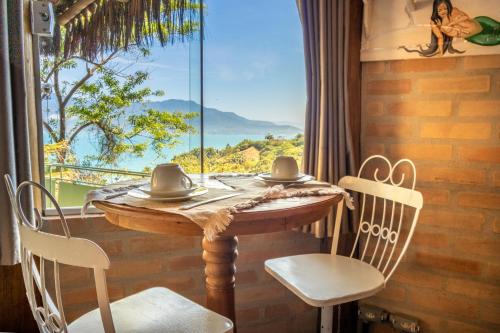 a table and chairs in a room with a large window at Le Refuge Suites in Ilhabela