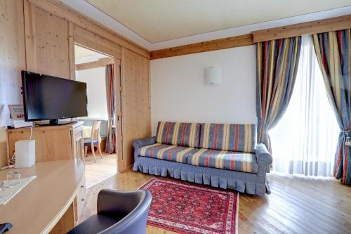 a living room with a couch and a flat screen tv at Leading Relax Hotel Maria in Moena