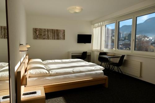 a bedroom with two beds and a desk and a window at Hôtel Oasis in Moutier