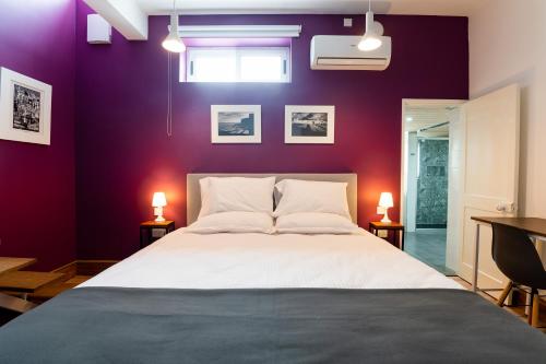 um quarto com uma cama grande e paredes roxas em Monreal Boutique Townhouse - R024RM6 em Paola