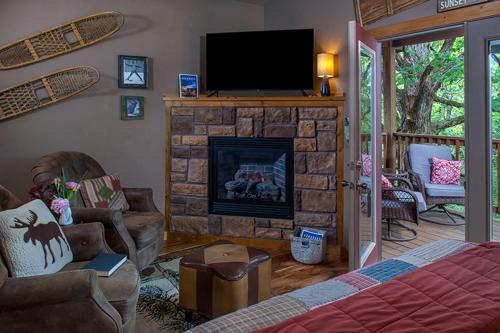 a living room with a fireplace and a television at Eureka Sunset Cabins in Eureka Springs