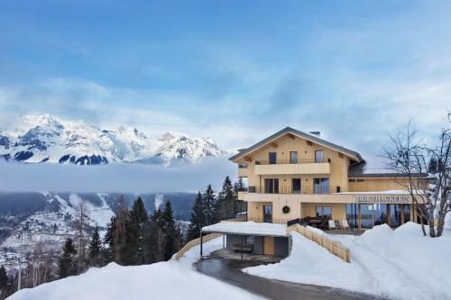 a building in the snow with mountains in the background at Holzhackerin - the charming Haus am Berg in Schladming