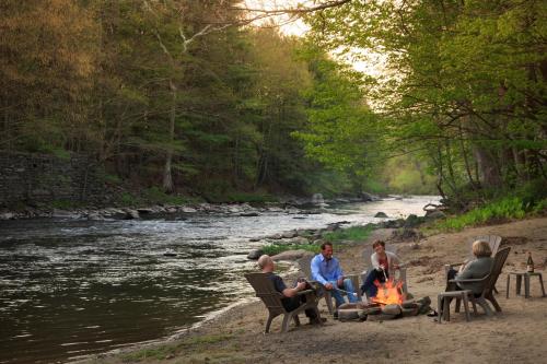 a group of people sitting around a fire next to a river at Settlers Inn in Hawley