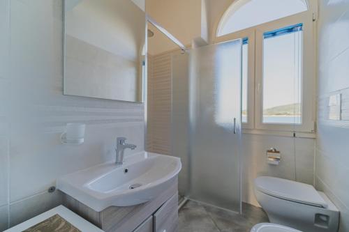 a white bathroom with a sink and a toilet at Appartamenti Brezza Marina a Campo in Marina di Campo