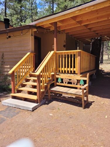 Cabaña de madera con escalera y porche en Greer Point Trails End Cabins, en Greer