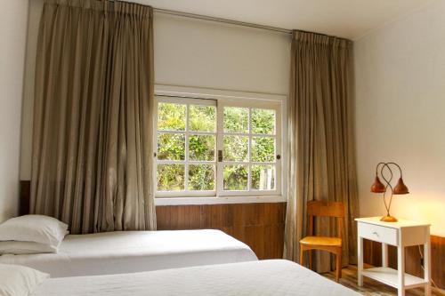 1 dormitorio con 2 camas y ventana en Hotel Village da Serra, en São Francisco de Paula