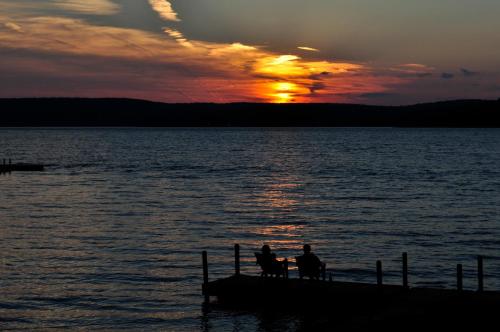 two people sitting on a dock in the water at sunset at Silver Birches Resort in Hawley