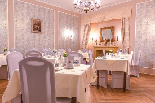 a restaurant with white tables and chairs and a chandelier at Hotel Römerhof in Baden-Baden