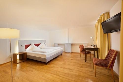 a hotel room with a bed and a desk at AKZENT Brauerei Hotel Hirsch in Ottobeuren