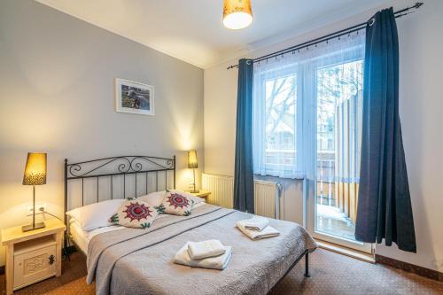 a bedroom with a bed and a large window at Willa Cicha Woda Centrum in Zakopane