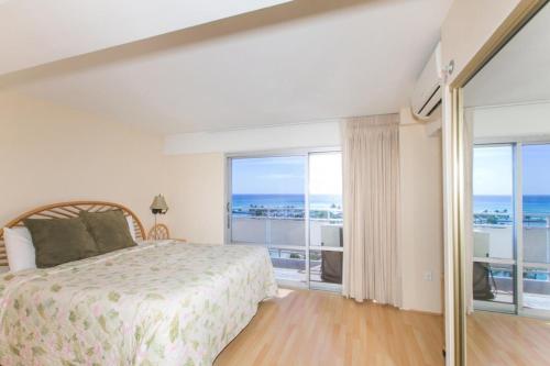 een slaapkamer met een bed en een groot raam bij Ilikai Tower 943 Yacht Harbor View 2BR in Honolulu