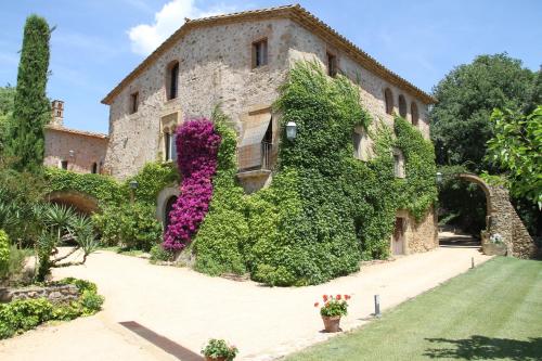 an old stone building with flowers on it at Mas Vilosa Bed and Breakfast in Corçà