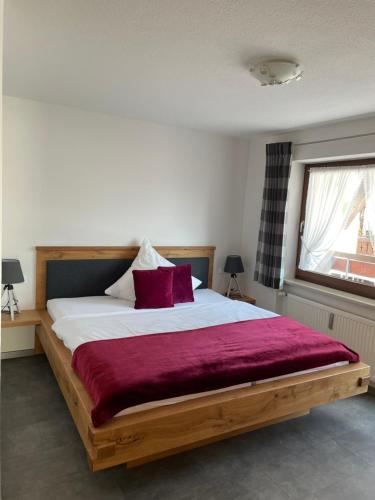 a bedroom with a wooden bed with a red blanket at Ferienwohnungen Ellen Müller in Fischen