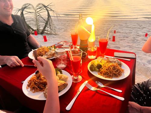 a group of people sitting at a table with plates of spaghetti at Manta Stay Thoddoo, Maldives in Thoddoo