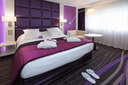 a hotel room with a large bed with purple walls at Mercure Strasbourg Aéroport in Ostwald