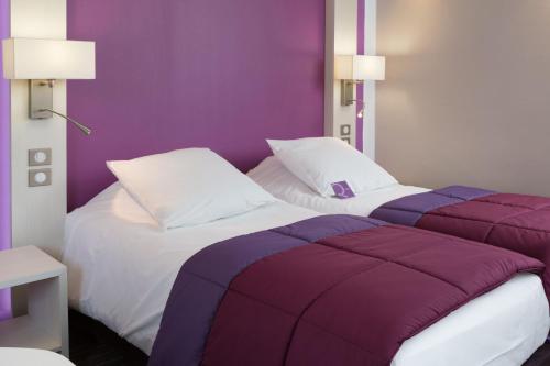 two beds in a room with purple walls at Mercure Strasbourg Aéroport in Ostwald
