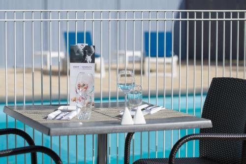 a table with two wine glasses on top of it at Mercure Strasbourg Aéroport in Ostwald