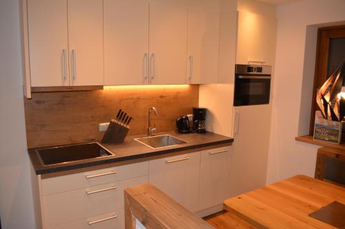 a kitchen with white cabinets and a sink and a table at Ramseiderhof in Saalfelden am Steinernen Meer