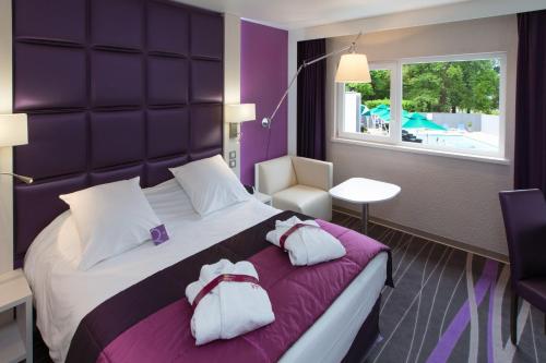 Una habitación de hotel con una cama grande con dos bolsas. en Mercure Strasbourg Aéroport, en Ostwald