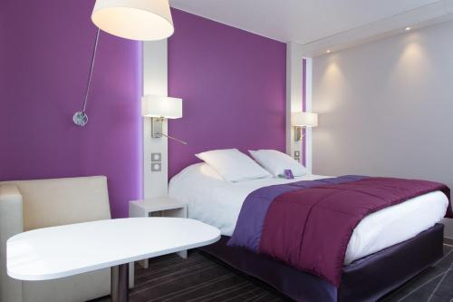 a bedroom with a bed and a purple wall at Mercure Strasbourg Aéroport in Ostwald