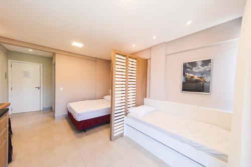 a small bedroom with two beds and a kitchen at RESIDENCIAL MAR BLUE in Bombinhas