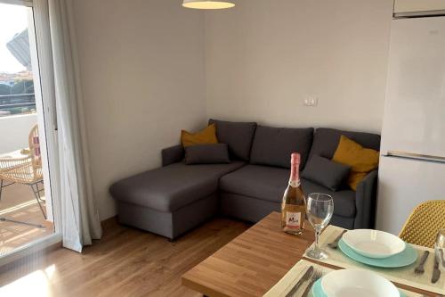 a living room with a couch and a table with a bottle of wine at Precioso Apartamento, luminoso, equipado in Torre de Benagalbón