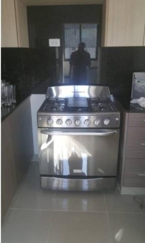 a stove in a kitchen with a person in the background at Moderno Apartamento amueblado Full 3 habitaciones, wifi, Netflix in Santiago de los Caballeros