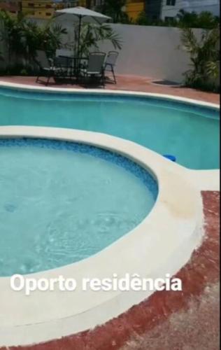 a blue swimming pool with a table and an umbrella at Moderno Apartamento amueblado Full 3 habitaciones, wifi, Netflix in Santiago de los Caballeros