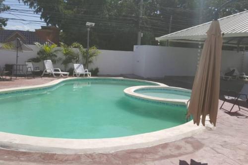 a large swimming pool with an umbrella and chairs at Moderno Apartamento amueblado Full 3 habitaciones, wifi, Netflix in Santiago de los Caballeros