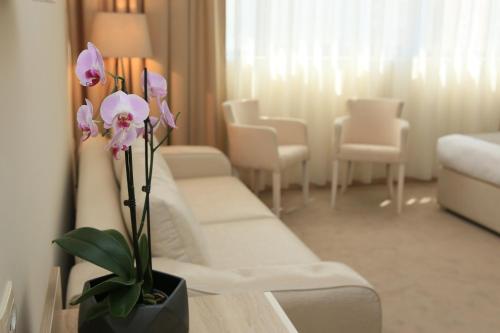 a living room with a white couch and flowers on a table at Hotel Leone in Međugorje