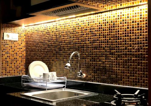 uma cozinha com um lavatório e uma parede de tijolos em Apartement Grand Asia Afrika Bandung by House Of Tofi em Bandung