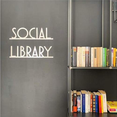 una estantería llena de libros con las palabras biblioteca social en Lontani da Casa asd en Borgofranco dʼIvrea