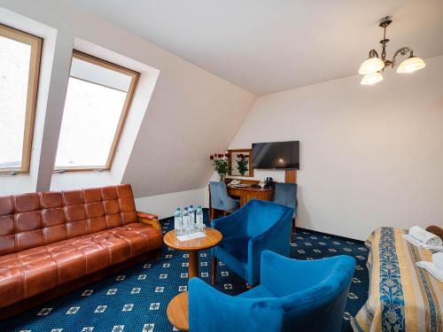 a living room with a couch and blue chairs at Hotel Liptakówka in Białka Tatrzanska