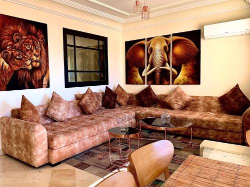 - un salon avec un canapé brun et des peintures murales dans l'établissement Sab 9 - Great View Over Hassan Mosque. Luxurious 3 Bedrooms & 2,5 Bathrooms, à Casablanca