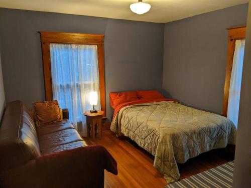 a bedroom with a bed and a couch and a window at Large Bakery Apartment - Central Downtown Location in Fredonia