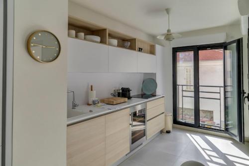 eine Küche mit weißen Schränken und einer Uhr an der Wand in der Unterkunft IMMOGROOM- Modern - Elegant - Close to the beach -AC in Cannes