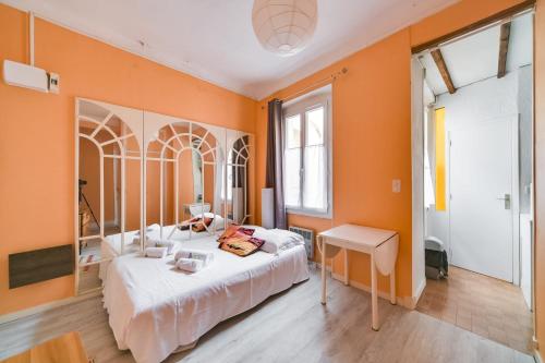カンヌにあるIMMOGROOM- Close to the Palais des festivals- Wifiのオレンジ色の壁のベッドルーム1室、ベッド1台、テーブルが備わります。