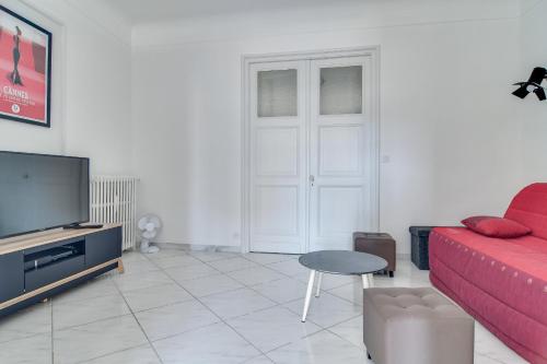un salon avec un canapé rouge et une télévision dans l'établissement IMMOGROOM - Sea View - Balcony - 5 min from the beach - AC - Wifi, à Cannes