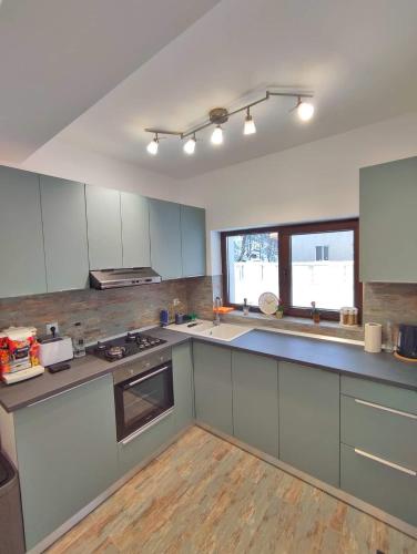 a large kitchen with white cabinets and a window at Mountain Break Azuga in Azuga